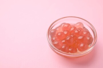 Bright tapioca pearls in bowl on pink background, closeup. Space for text