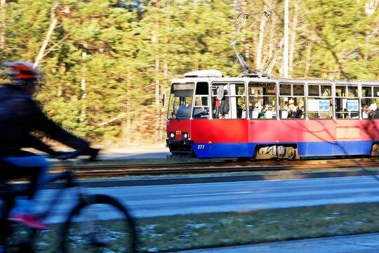 tram with panning motion effect during sunny day, blurred background and fat-moving cyclist on the foreground