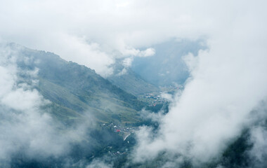 Obraz premium aerial view through clouds to valley with mountain villages