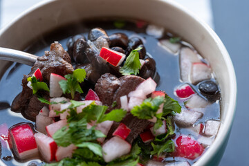 Platillo de frijol con puerco acompañado de rábano picado y cilantro