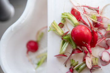 rábano rojo entero y residuos sobre tabla blanca de cocina listo para lavarse