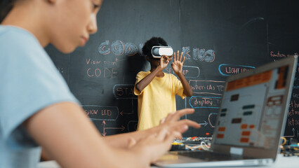 Closeup of school girl hand coding program while african student using VR interact with metaworld....