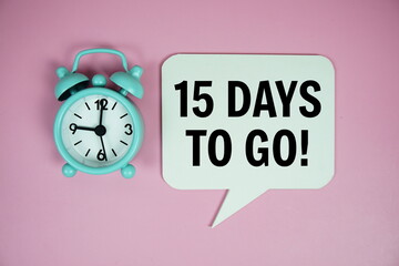 15 Days to go text on speech bluble with alarm clock top view on pink background