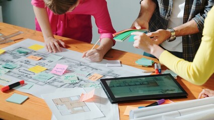 Top view of civil engineer writing and planning by using sticky notes to brainstorm idea. Top down aerial view of business people taking a note at table with project plans and equipments. Symposium.