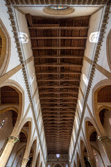 Upward interior view of Santa Croce Basilica showcasing wooden truss ceiling and Gothic arches in summer