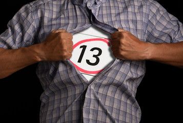 Man tears off his shirt, showing sign with number 13, symbolizing superstition and inner fear.