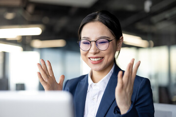 Happy asian businesswoman in office celebrating victory with laptop, showing excitement and success...