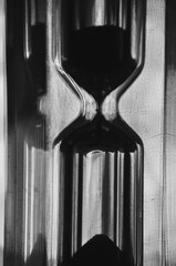 A black-and-white hourglass close-up measuring time with flowing sand transparent glass