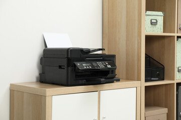 Modern printer with paper on wooden nightstand in office