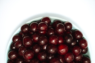 A full plate of ripe red cherries on the white background
