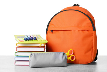 Backpack with different school stationery on light grey table against white background