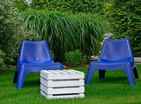 biały stolik ze skrzynki i niebieskie fotele ogrodowe na trawie, blue plastic garden chair on grass, garden table made of box, blue chairs and white wooden box in garden,  fotel ogrodowy "PS VAGO"