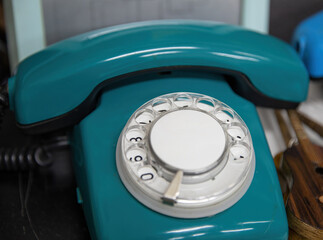 Old rotary telephone with a green handset.