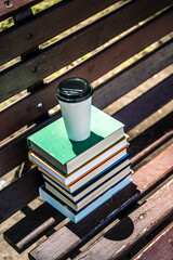 Stack of books and cup of coffee on the street in the park. Study, education, university concept.
