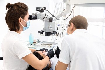 Obraz premium Difficult cases in stomatology. Back view of two dentists making treatment in modern dental office