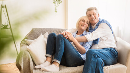 Love lives forever! Loving senior couple embracing, sitting on sofa and enjoying spending time...