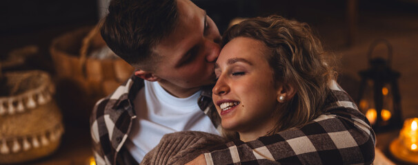 Beautiful young loving couple relaxing near fireplace in bed at home. Happy spouses enjoying lazy...