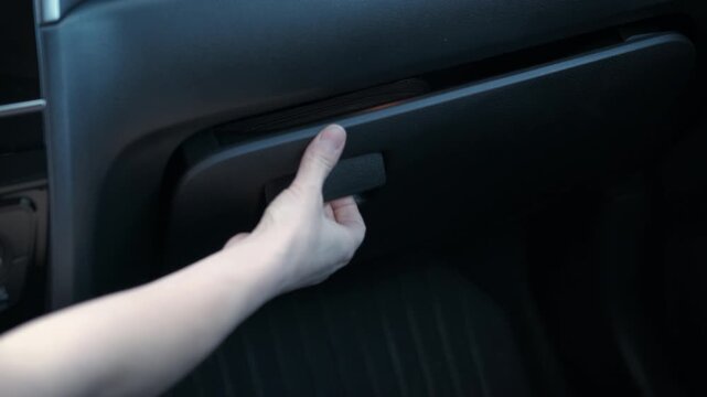 Store in car glove box. A woman open the store compartment with something interesting inside the auto.