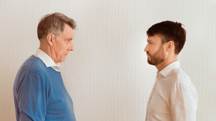 Conflict Between Generations. Elderly Man And Mature Son Looking Severely At Each Other Standing...