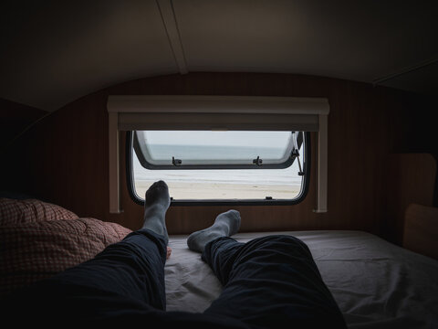 Morning views to the beach through the motor home window lying on bed pov