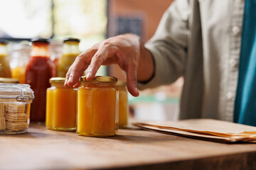 Close-up of person touching jars of nutritious honey in a zero-waste store. Product manufactured...