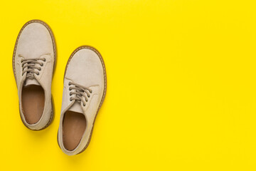 Beige suede shoes on color background, top view