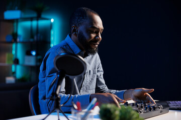 Artist filming DJ mixing tutorial in apartment studio, showing examples of sampling on sound controller to viewers. Entertainer showing modern musical equipment to subscribers in living room