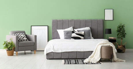Comfortable bed, picture frame and armchair in stylish bedroom