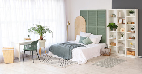 Interior of light bedroom with shelf unit, plants and table