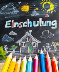 Szene mit bunten Kreidestücken& verspielten Zeichnungen auf einer Schultafel. Die Worte "Einschulung" sind deutlich zu lesen& fangen die Aufregung der Einschulung& den Beginn des neuen Schuljahr ein