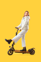Young woman riding electric scooter on yellow background © Pixel-Shot