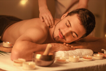 Young man getting massage in dark spa salon