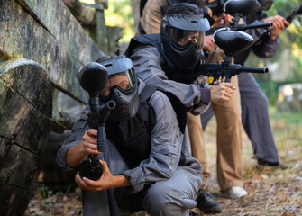 Group of paintball players aiming and shooting with guns