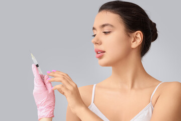 Young woman and hand with beauty injection on light background, closeup