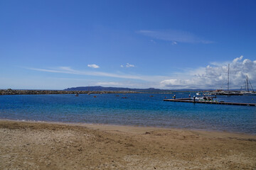 Obraz premium beach and harbor wall of l'Estartit at a sunny day, mountains around Begur at the horizon, Mediterranean Sea, Catalonia, Costa Brava, Barcelona, Girona, Spain