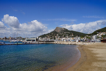 beach near the port of l'Estartit on a sunny day, behind it the town centre of l'Estartit and high mountains, Mediterranean Sea, Catalonia, Costa Brava, Barcelona, ​​​​Girona, Spain