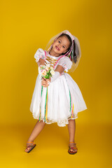 Cheerful child dressed as a bride holding a bouquet of flowers and posing for the camera.