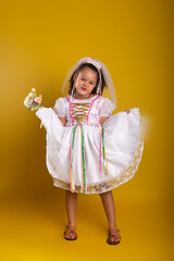 Cheerful child dressed as a bride holding a bouquet of flowers and posing for the camera.