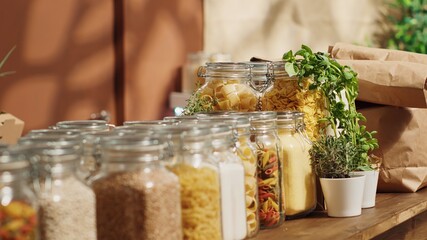 Close up on bulk food items in reusable glass jars used by zero waste supermarket to lower climate impact. Eco friendly local shop pantry staples in decomposable packaging, panning shot