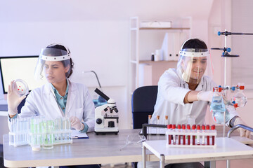 Young chemists with protective masks working at table in laboratory