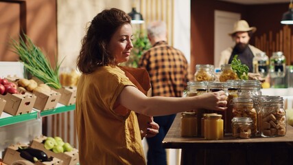 Happy woman in zero waste supermarket using decomposable paper bag while shopping for organic pantry staples. Smiling customer in local neighborhood shop with no single use plastics policy