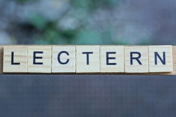 text the word lectern from brown wooden small letters with black font on an gray background