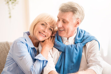 Happy mature couple enjoying time at home and relaxing on sofa