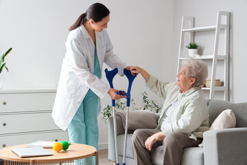 Obraz premium Senior woman and physical therapist with crutches at home