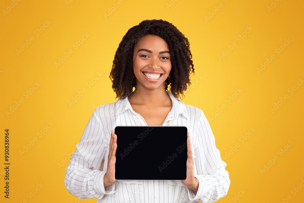 Poster black woman showing blank tablet computer screen at studio over yellow background. empty space, mock