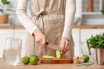 Young woman cutting lime for preparation mojito in kitchen