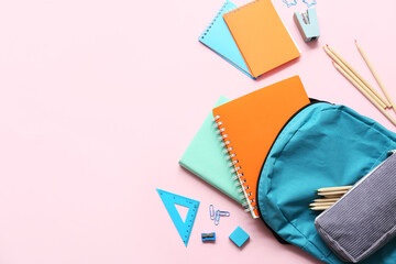 School backpack with different stationery supplies on pink background