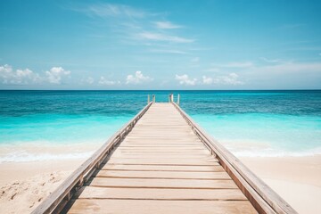 Fototapeta premium Wooden pier extending into turquoise ocean with white sand beach and clear water in a wide-angle view.