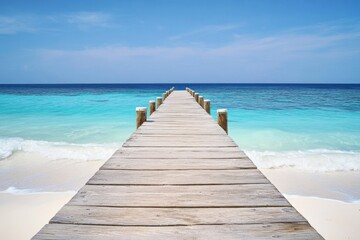 Fototapeta premium Wooden pier extending into turquoise ocean with white sand beach and clear water in a wide-angle view.