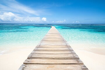 Wooden pier extending into turquoise ocean with white sand beach and clear water in a wide-angle view.